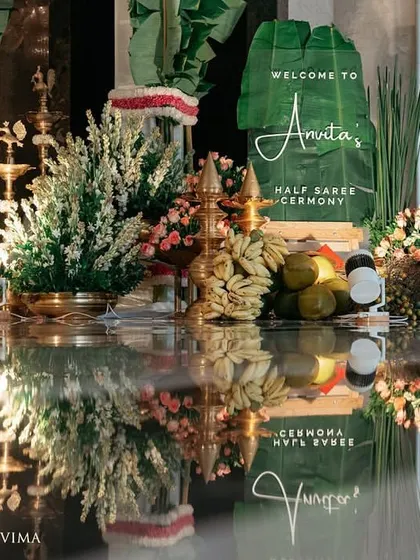 The entrance to a half-saree ceremony, adorned with fragrant jasmine garlands and banana leaves. The reflection on the polished floor doubles the beauty of this traditional South Indian decor.