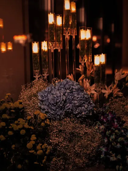 We love layering light and texture. Here, tall, elegant candle holders rise from a bed of blue hydrangeas and delicate baby's breath, creating a multi-dimensional centerpiece that is both modern and timeless.