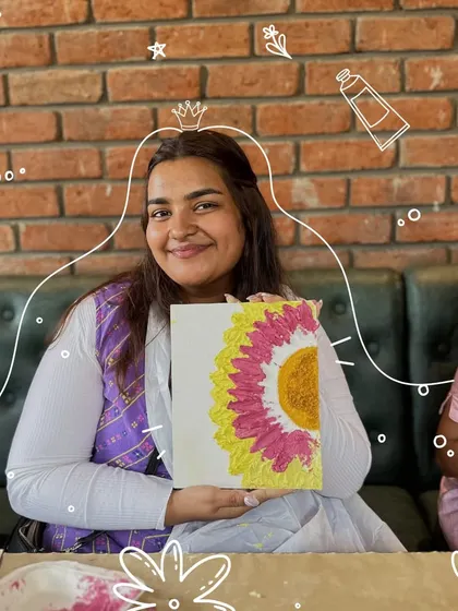A participant happily shows off her completed sunflower painting. Our workshops are beginner-friendly, ensuring everyone leaves with a piece of art they are proud to have made themselves.