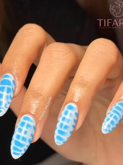 Another angle showcasing the depth and detail in this blue and white nail art. The almond shape of the nail perfectly complements the elongated pattern.