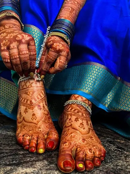A stunning close-up of the bride's feet, adorned with silver anklets and a rich, dark henna stain.