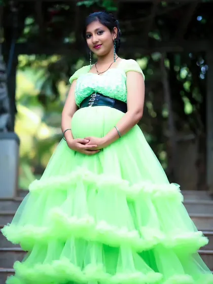 A beautiful portrait of an expectant mother in a lime green ruffled gown, posing on a stone staircase.