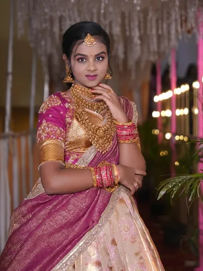 A young client looking radiant at her half-saree function in a custom-designed pink and gold Langa Dhawani.