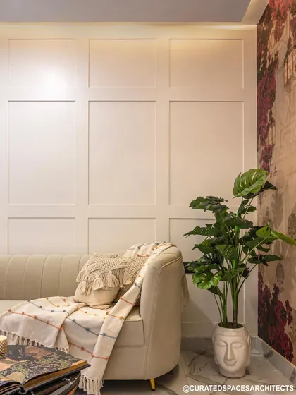 I love using wall paneling to add texture and elegance. Here, the simple white paneling provides a clean backdrop for the cozy sofa and a touch of greenery.