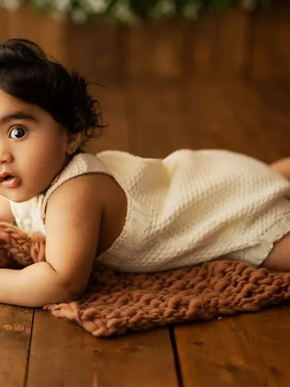 A curious baby doing tummy time on a rustic wooden floor. This angle captures their strength and determination as they explore the world.