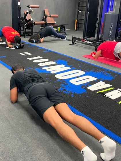 The calm before the storm, or maybe the quiet after. Members hold a plank together, sharing the burn and the accomplishment.