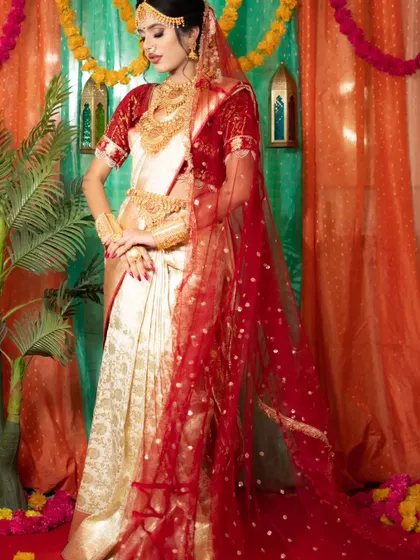 A complete South Indian bridal look featuring a traditional off-white and red silk saree with authentic temple jewellery, all available for rent.