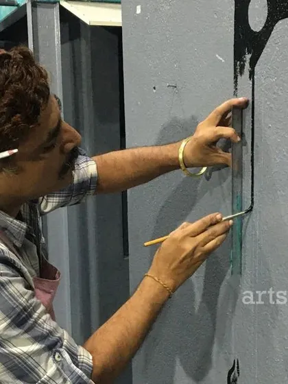 Precision in action. Our artist uses a ruler to ensure perfectly straight lines on a graphic mural, demonstrating our commitment to quality and detail in every project.