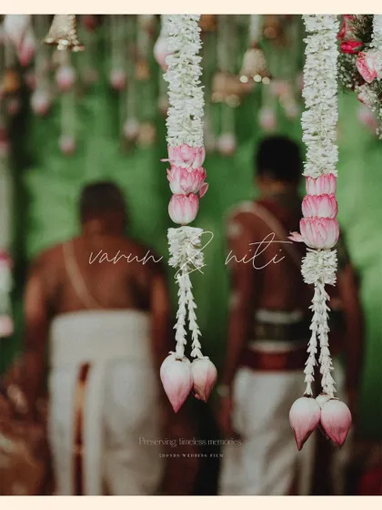 An artistic shot focusing on the beautiful floral garlands hanging in the mandap, with the couple blurred in the background.