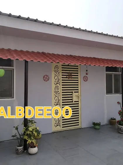 A simple and practical prefabricated house on a terrace in Indirapuram. The extended metal roof creates a nice shaded porch area, decorated with potted plants.