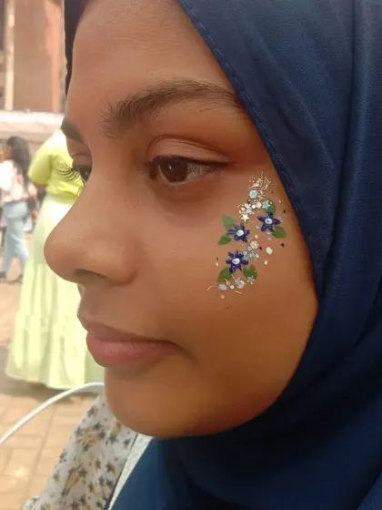 A delicate spray of blue and white flowers with silver glitter, placed beautifully along the cheek.