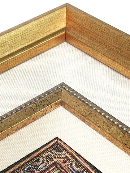 A detailed look at the corner of the framed rug, showcasing the combination of a golden fillet and a textured fabric mat. These layers add depth and a sense of luxury to the final piece.
