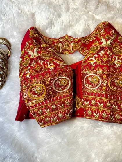 This image shows the sleeve detail of our red bird-themed blouse. You can see the texture and dimension created by combining Zardozi, threadwork, and beadwork to form the peacock and floral patterns.