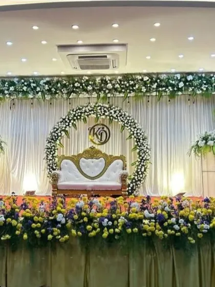 A reception stage featuring a circular floral frame with a custom monogram, bordered by colorful flowers along the base.
