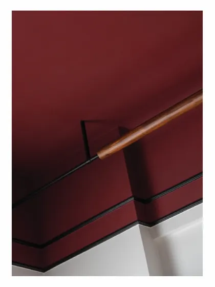 To avoid a false ceiling, we designed this custom lighting solution. A simple wooden rod wraps around a metal rod, housing an indirect light source that casts a dim, warm glow onto the Marsala-colored ceiling.