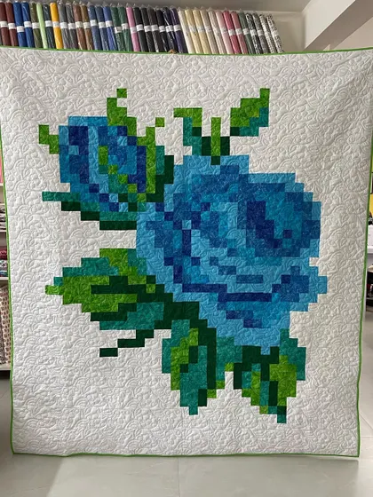 A beautiful pixelated rose quilt in shades of blue and green. This modern technique uses small squares of fabric to create a large, stunning image, perfect for a statement wall hanging.