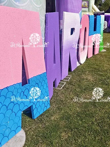 A close-up of the custom-painted marquee letters for a mermaid theme, showing the scale-like texture and gradient colors.