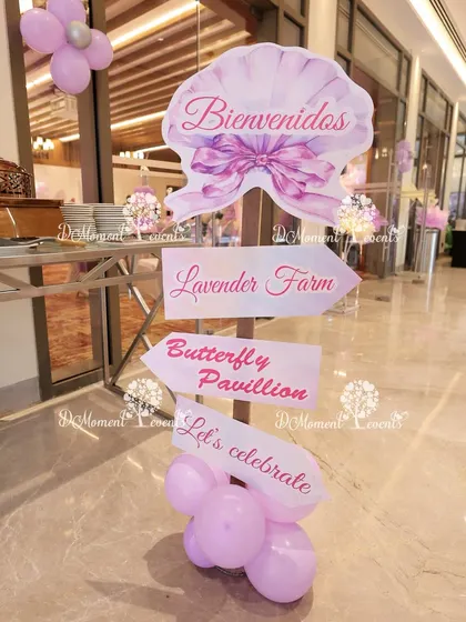 A whimsical directional signpost for a butterfly and fairy party, pointing guests to the "Lavender Farm" and "Butterfly Pavilion."