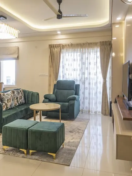 The strategic placement of furniture and lighting creates a warm and inviting atmosphere in this living room. The sheer curtains diffuse natural light, making the space feel bright and airy.