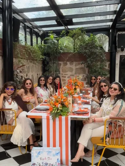 The beautifully set long table, with a striped runner, lush orange floral centerpieces, and personalized place settings.