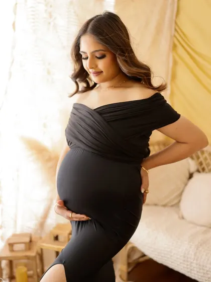 A classic and elegant portrait in a black bodycon dress. The soft, natural light from the window highlights her beautiful silhouette.