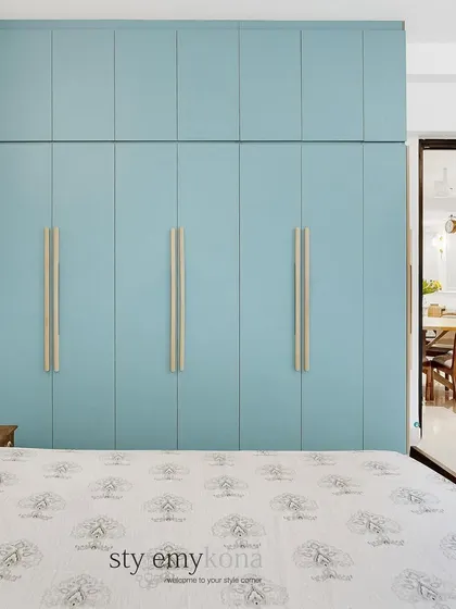 This simple guest room is elevated by its beautiful blue wardrobe. The sleek design and custom wooden handles add a touch of class and personality to the minimal decor.