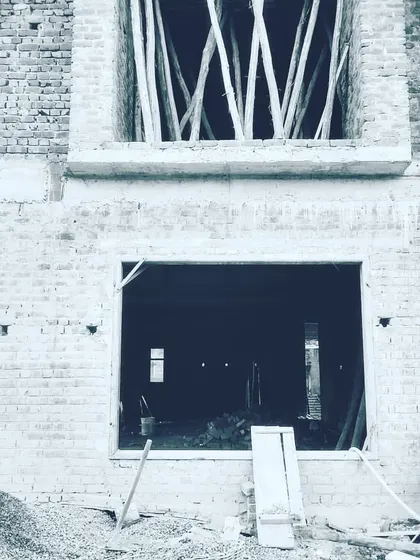 A black and white shot from a site visit, focusing on the raw structural openings of a building under construction. This is where the vision starts to take shape, with every window and door frame placed according to the architectural plan.
