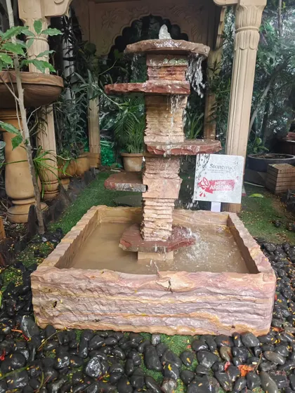 The natural stone cascading fountain, with its rough-hewn texture, blends seamlessly into a garden environment.