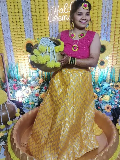 The bride posing inside a large decorative 'urli' during her Haldi ceremony, a unique seating idea that we provide.