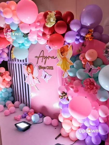 A colorful fairy-themed party with a vibrant balloon arch.