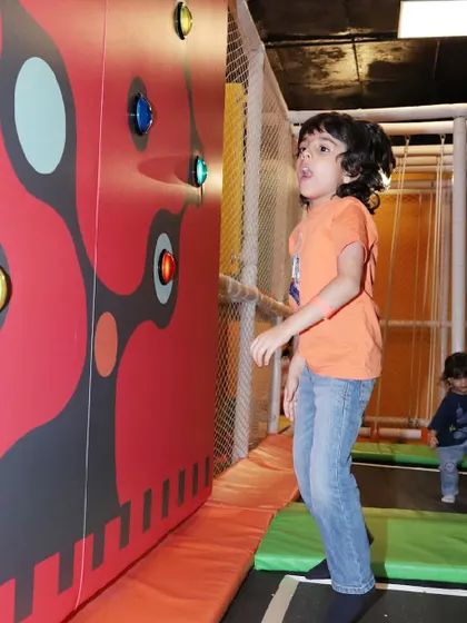 A young boy jumps on the trampoline in front of the interactive light wall.