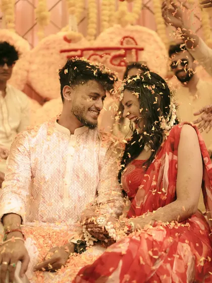 A happy couple sharing a moment under a shower of flower petals at their Haldi.