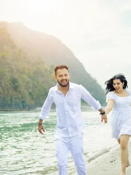 A fun and energetic shot of a couple running barefoot along the riverbank, their smiles capturing the joy of the moment.