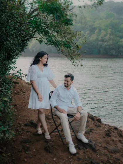 A serene lakeside portrait near Pune. The composition, with the bride standing by the seated groom, feels calm and contemplative, perfectly matching the tranquil environment.