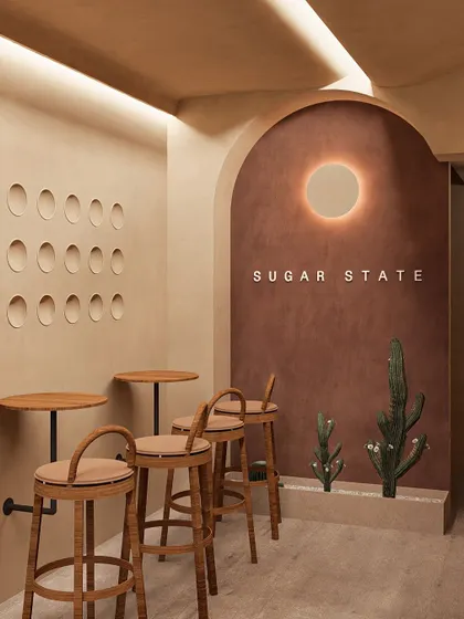 For the Sugar State bakery, I designed a space that feels both sweet and earthy. The terracotta-colored accent wall with a halo light serves as a focal point, while the minimalist bar seating and wall perforations add a touch of modern, playful geometry.