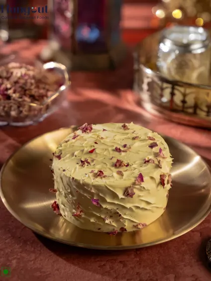 A perfect example of our fusion desserts, this is the Pistachio Rasmalai Bento Cake. It combines the traditional Indian flavor of rasmalai with nutty pistachio, all wrapped in a modern bento cake format and decorated with delicate rose petals.