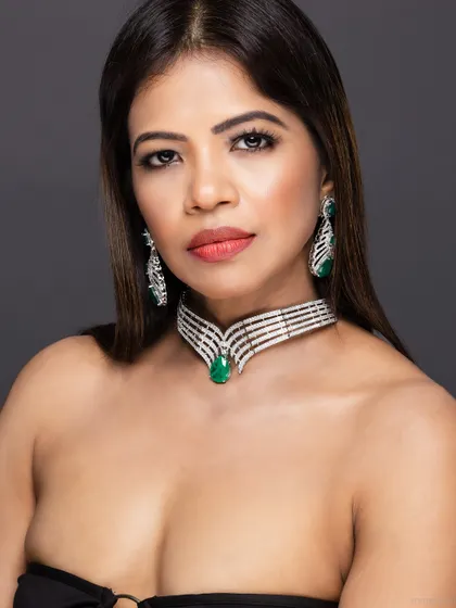 A close-up of a model wearing a stunning diamond and emerald choker and earring set. The focus is entirely on the sparkle and design of the pieces.