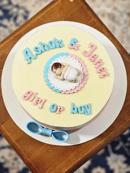 A top-down view of the gender reveal cake, showing the cute fondant baby and the pink and blue color scheme.