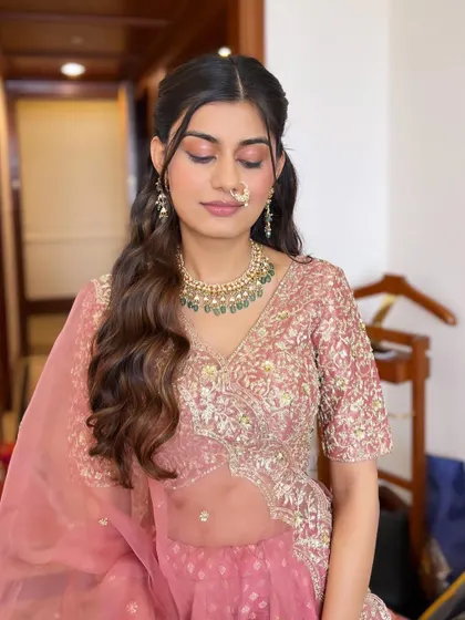 A close-up of this enchanting look, showing the blend of coral and brown eyeshadow. The half-up hairstyle with soft waves completes this romantic and modern style.