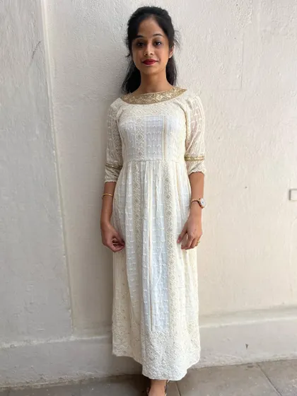 An elegant full-length cream kurta with a golden lace neckline, worn by a client.