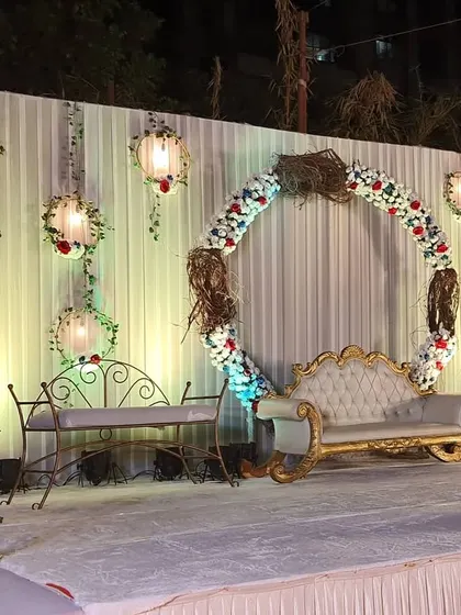 A classic reception stage design with a rustic twist. We created a large floral ring as the centerpiece, surrounded by hanging lanterns and elegant seating for the couple.