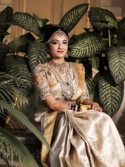 Seated amidst lush greenery, this bride looks like a goddess. The contrast of her golden attire with the natural background is simply stunning.