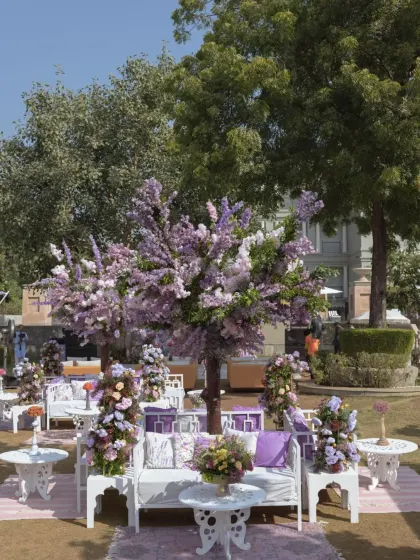 A wide view of the lavender carnival setup, featuring custom-made blossom trees and elegant white lounge furniture.