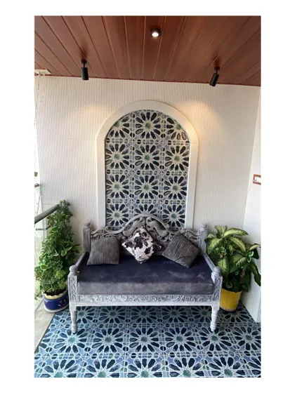 A straight-on view of the balcony's seating area. The intricate tilework in the arched niche acts as a beautiful backdrop for the ornate bench, creating a perfect spot to enjoy a cup of tea.