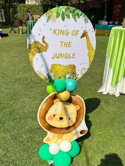 A "King of the Jungle" sign with a cute lion cutout, used as a decorative stand for an outdoor safari party.