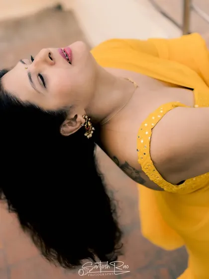 A dramatic pose in a bright yellow satin saree, paired with a custom-designed blouse with mirror work.