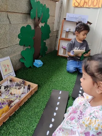 One child pretends to be at school while another explores a box of farm animals. In our role-play area, multiple stories can happen at once, driven by the children's interests.