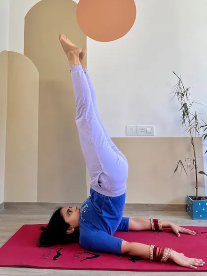 An unsupported shoulderstand, showing the progression from the supported version. This requires more core and back strength to hold the body in a straight line without the help of the hands.