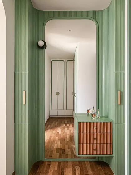 A closer look at the custom fluted vanity area, with its mix of green paint and natural wood drawers, reflecting the playful material palette of the room.