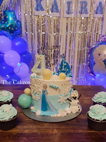 A magical Frozen themed cake and matching cupcakes for a winter wonderland party. The cake features Elsa and Olaf, with edible snowflakes and ice-blue details, creating a scene straight out of Arendelle.